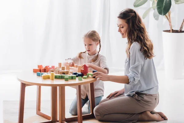 Вид збоку щасливої матері грає блоки з чарівною маленькою дитиною — стокове фото
