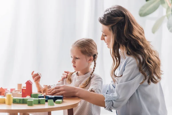 Side view of happy mother playing blocks with little child — Stock Photo