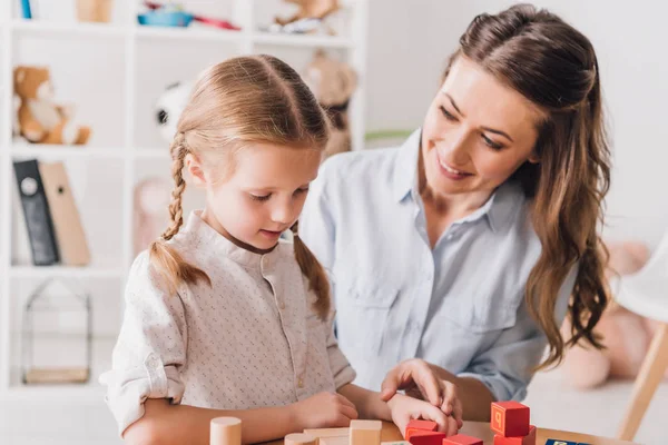 Feliz madre jugando bloques con el niño pequeño - foto de stock