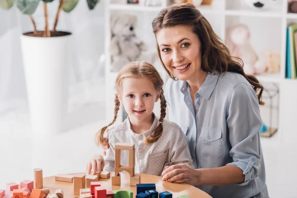 Smiling mother and child looking at camera while playing with blocks — Stock Photo