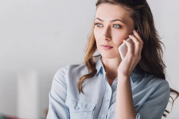 Close-up portrait of serious adult woman talking by phone and looking away — Stock Photo