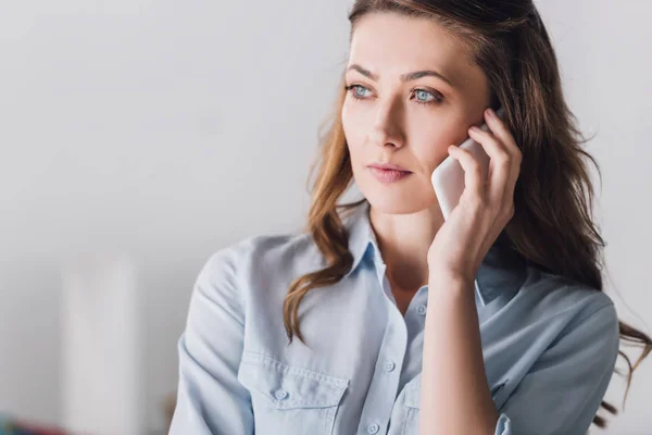 Retrato de cerca de la mujer adulta grave hablando por teléfono y mirando hacia otro lado - foto de stock