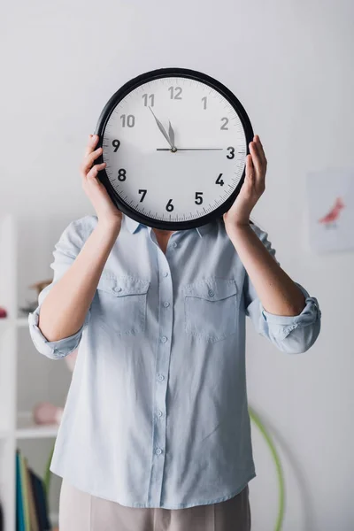 Nahaufnahme Porträt einer Frau im Hemd, die Gesicht mit Uhr verdeckt — Stockfoto