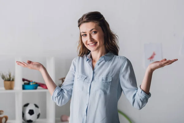 Smiling adult woman shrugging shoulders and looking at camera — Stock Photo