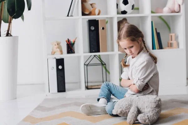 Depressed little child sitting on floor with teddy bear — Stock Photo