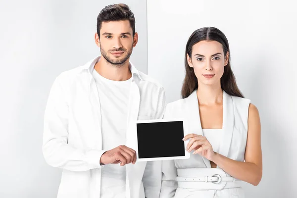 Sorridente coppia adulta in totale bianco mostrando schermo bianco sullo schermo del tablet digitale — Foto stock