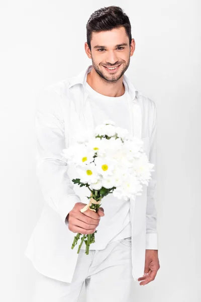 Schöner lächelnder Mann in völligem Weiß mit einem Strauß weißer Blumen auf weißem Grund — Stockfoto