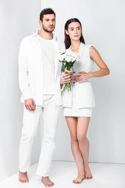 Adult barefoot couple in total white posing with bouquet — Stock Photo