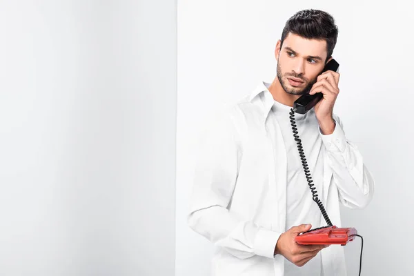 Close up of handsome man talking on retro red telephone — Stock Photo