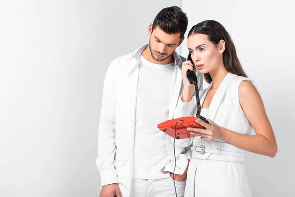 Casal adulto em branco total com telefone vermelho vintage atender chamada — Fotografia de Stock