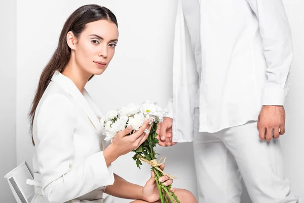 Erwachsene schöne Frau in ganz Weiß, die sanft Blumen hält — Stockfoto