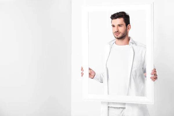 Handsome adult man in total white posing with frame — Stock Photo