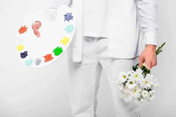 Close up of man holding palette with paint and flowers isolated on white — Stock Photo