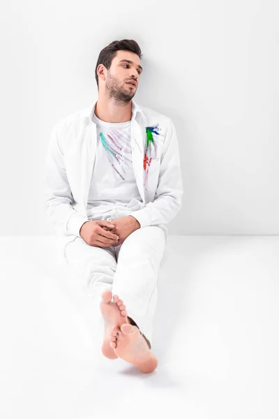 Adult barefoot man with painted clothes sitting on floor — Stock Photo