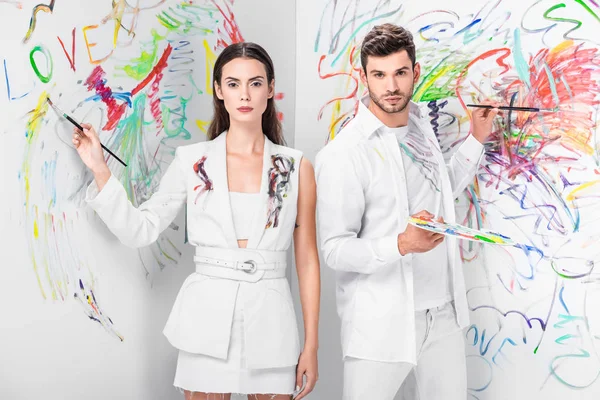 Tiro de moda de par em desenho branco total com pinturas na parede — Fotografia de Stock