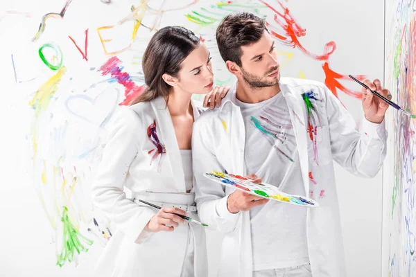 Close up of tender couple in total white drawing with paints on wall — Stock Photo