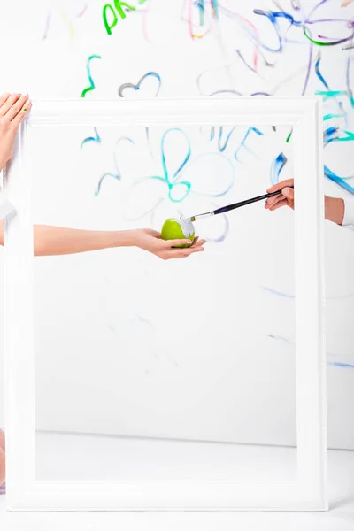 Close up of couple painting apple in frame with paintbrush — Stock Photo