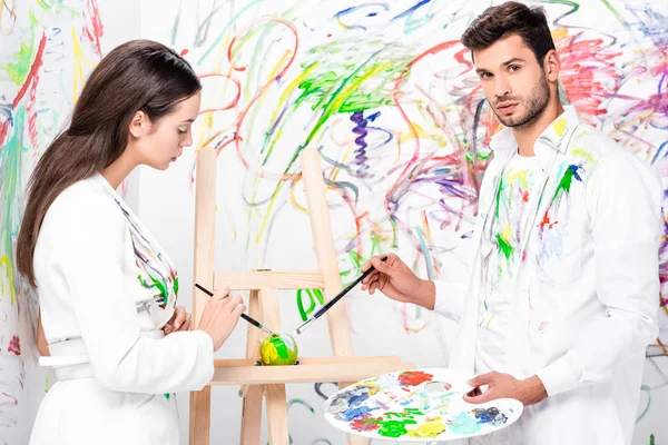 Adult couple painting green apple on easel — Stock Photo