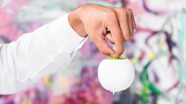 Крупним планом чоловіча рука тримає біле пофарбоване яблуко — стокове фото