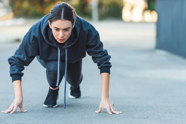 Active adult sportswoman exercising before jogging on street — Stock Photo