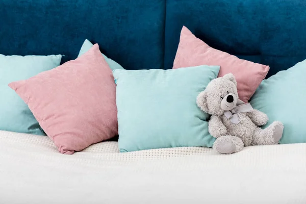 Teddy bear laying on the bed with pillows on background — Stock Photo