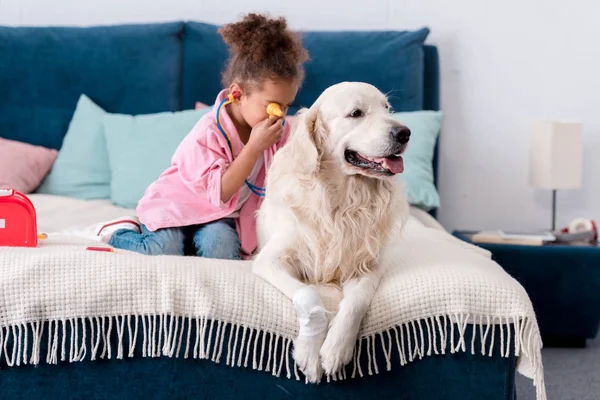 Bonito afro-americano criança brincando médico com ela ferido retriever — Fotografia de Stock