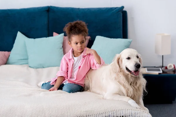 Confused african american kid leaned on her retriever — Stock Photo