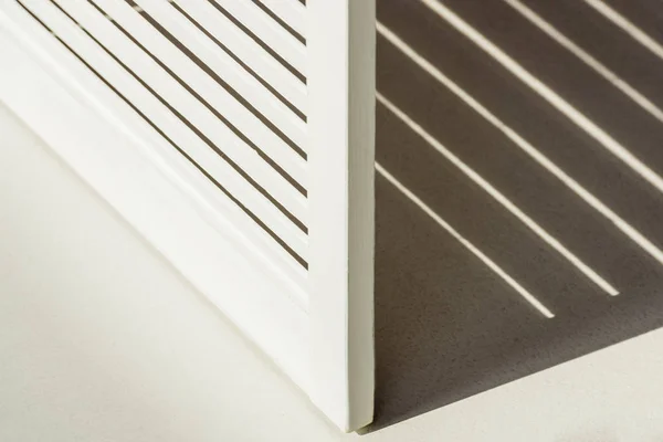 Gros plan de diviseur de pièce en bois blanc contre la lumière du jour avec ombre — Photo de stock