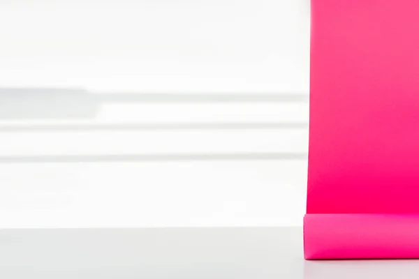 Close up of bright pink rolled out paper hangings on white wall with shadows — Stock Photo