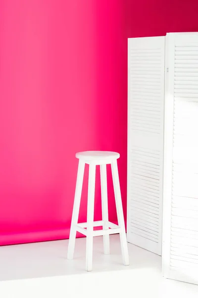 Divisor de quarto pintado branco e cadeira com papel de parede rosa brilhante no fundo — Fotografia de Stock