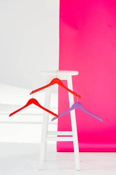 Multicolored painted hangers with white wooden chair — Stock Photo