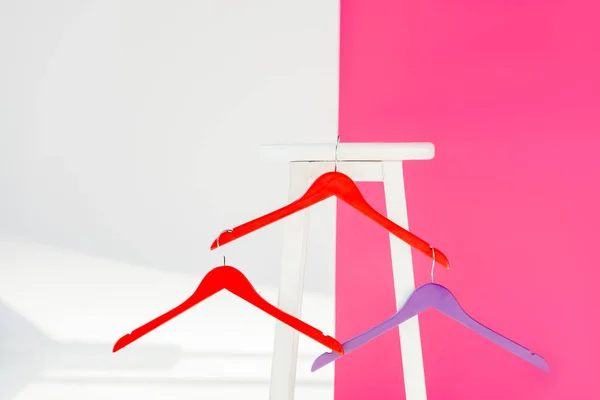 Nahaufnahme von bunt bemalten Kleiderbügeln mit weißem Holzstuhl — Stockfoto