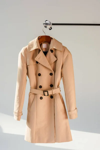 Imperméable beige avec ceinture et boutons noirs sur le cintre — Photo de stock