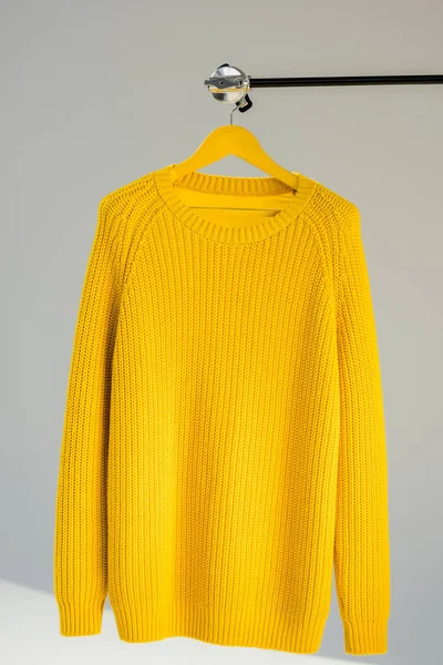 Knitted yellow sweater on hanger at grey background — Stock Photo