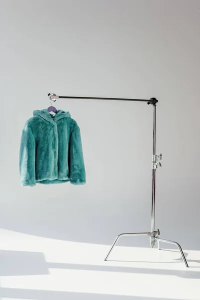 Fluffy green faux fur coat hanging on rack at grey background — Stock Photo