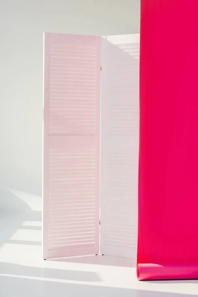 White room divider with bright pink rolled out wallpaper — Stock Photo