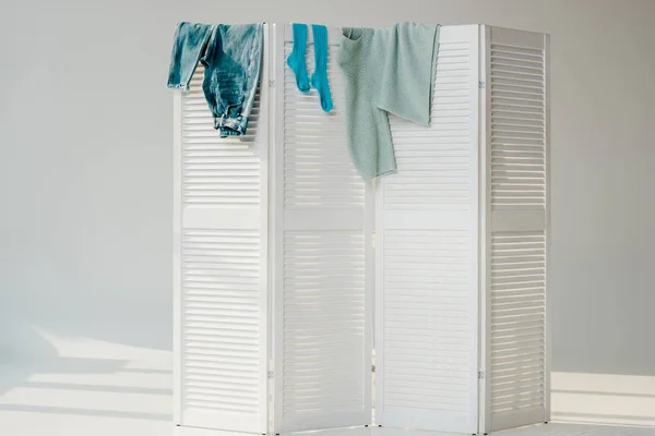 Roupas azuis penduradas no divisor de quarto branco — Fotografia de Stock