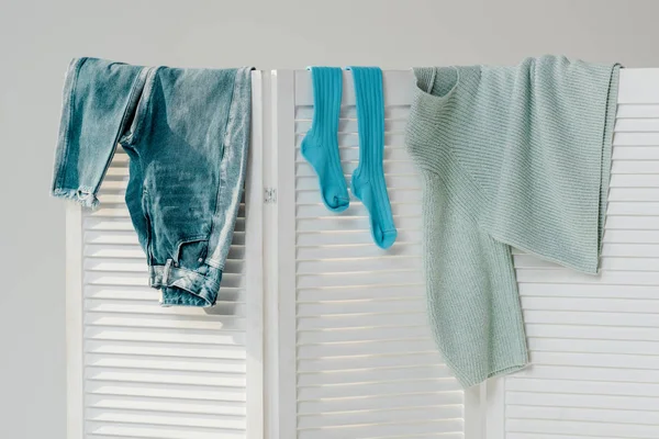 Gros plan de vêtements bleus suspendus sur diviseur de pièce blanche isolé sur gris — Photo de stock