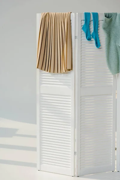 Roupas femininas multicoloridas penduradas no divisor de quarto branco — Fotografia de Stock