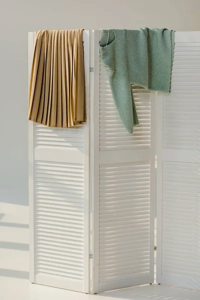 Roupas femininas multicoloridas penduradas no divisor de quarto branco — Fotografia de Stock