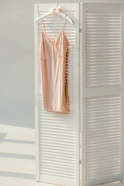Silk nightie with lace hanging on white room divider — Stock Photo