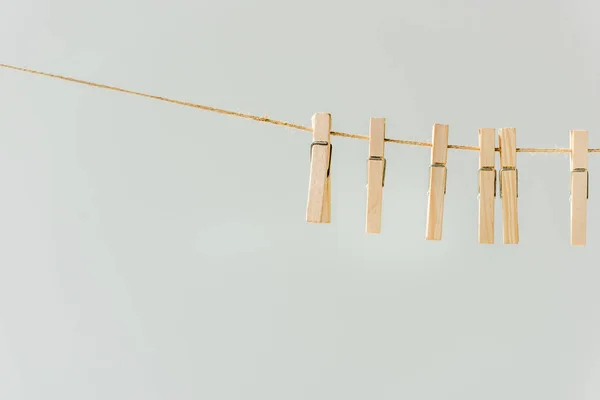 Gros plan de pinces à linge en bois crues accrochées à une corde à linge isolée sur du gris — Photo de stock