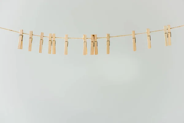 Primer plano de pinzas de tela de madera en bruto que cuelgan sobre tendedero aislado en gris - foto de stock