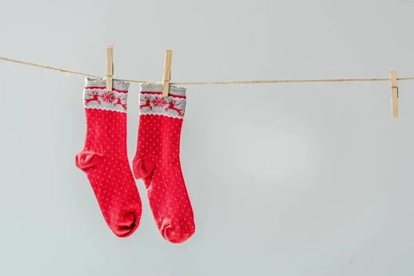 Close up of red festive winter socks hanging on clothesline with clothespins isolated on grey — Stock Photo