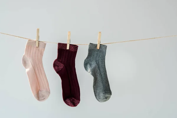 Gros plan de chaussettes multicolores brillantes accrochées à une corde à linge isolée sur du gris — Photo de stock