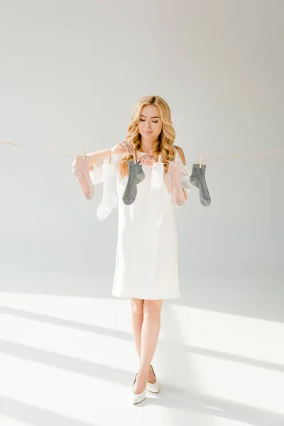 Belle femme avec des chaussettes suspendues sur la corde à linge — Photo de stock