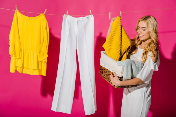 Hermosa mujer sacando ropa de canasta de mimbre - foto de stock