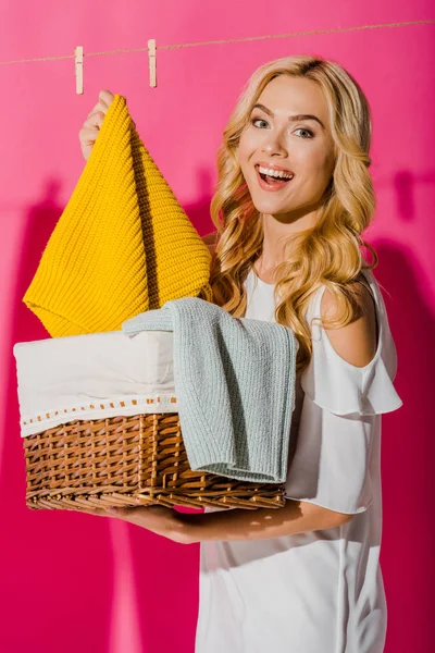 Крупным планом счастливая женщина достает одежду из плетеной корзины — стоковое фото