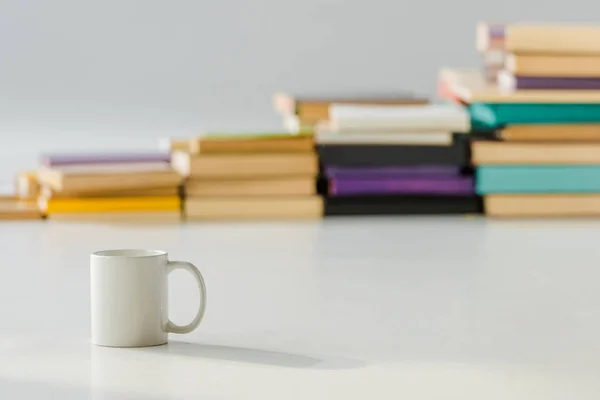 Primer plano de taza blanca con pila envejecida de libros sobre fondo — Stock Photo