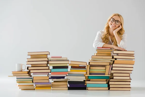 Bella donna in occhiali sognando vicino mucchio di libri — Foto stock